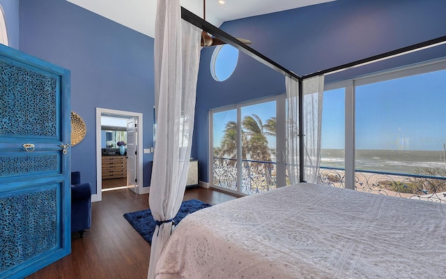 bedroom featuring high vaulted ceiling, dark hardwood / wood-style flooring, and a water view