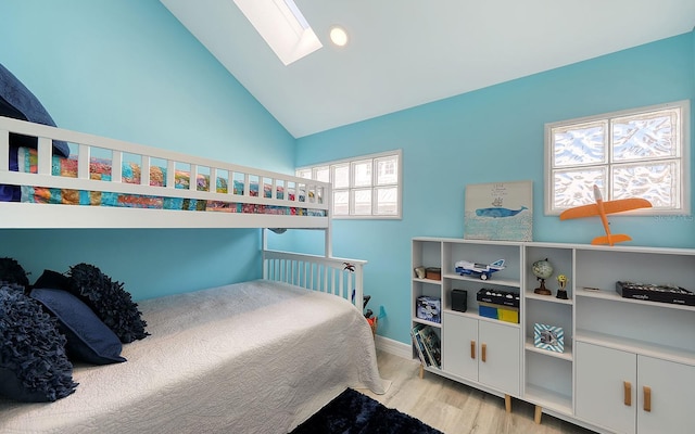 bedroom featuring light wood-type flooring, high vaulted ceiling, and a skylight