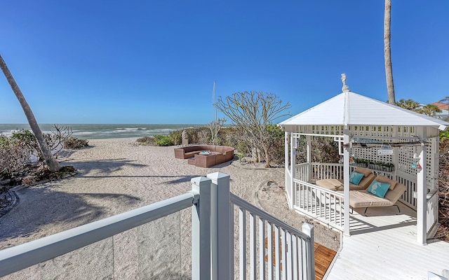 exterior space featuring a gazebo, an outdoor living space, a water view, and a beach view