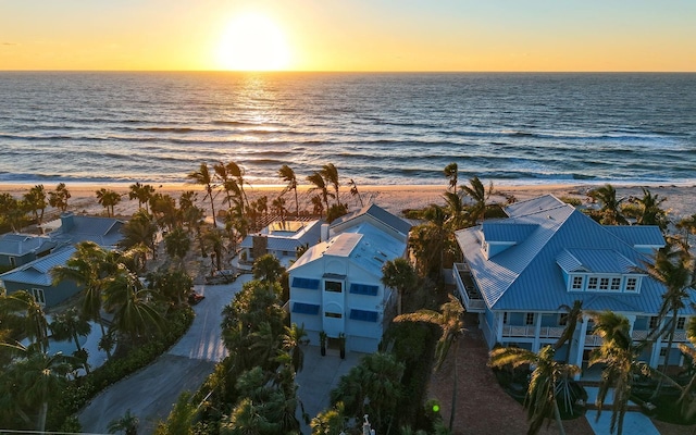 aerial view at dusk featuring a water view and a view of the beach