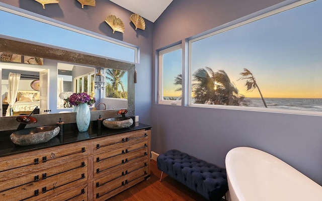 681 Casey Key Rd, Nokomis, FL 34275 - full bath featuring double vanity, a freestanding tub, wood finished floors, and vaulted ceiling