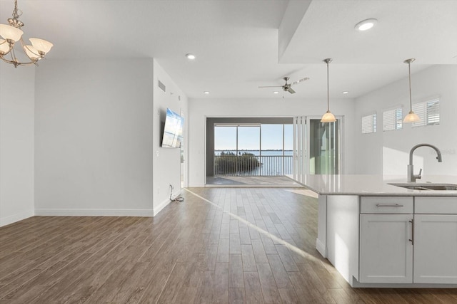 kitchen featuring sink, hanging light fixtures, dark wood-type flooring, white cabinets, and ceiling fan with notable chandelier