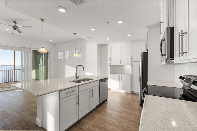 kitchen featuring sink, stainless steel appliances, white cabinetry, and an island with sink