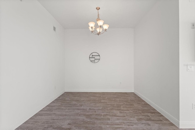 empty room with wood-type flooring and a chandelier