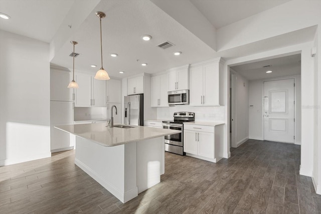 kitchen featuring pendant lighting, a kitchen island with sink, dark wood-type flooring, white cabinets, and stainless steel appliances