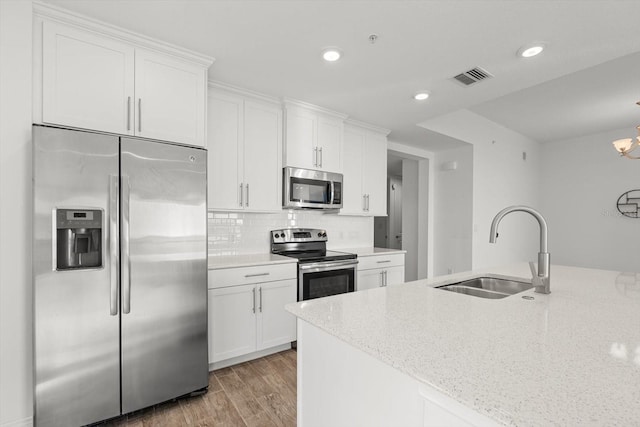 kitchen with light stone counters, white cabinetry, sink, and appliances with stainless steel finishes