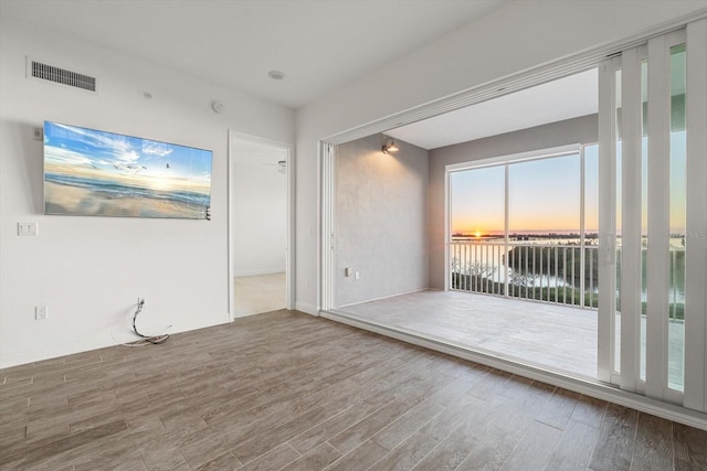 unfurnished room featuring hardwood / wood-style flooring and a water view