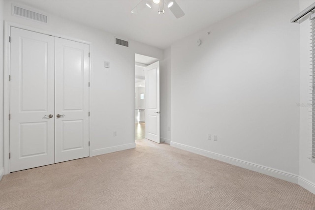 unfurnished bedroom with ceiling fan, a closet, and light colored carpet