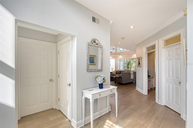 hallway featuring light wood-type flooring and crown molding