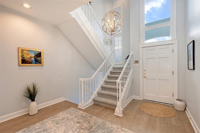 foyer featuring hardwood / wood-style floors, a towering ceiling, and an inviting chandelier