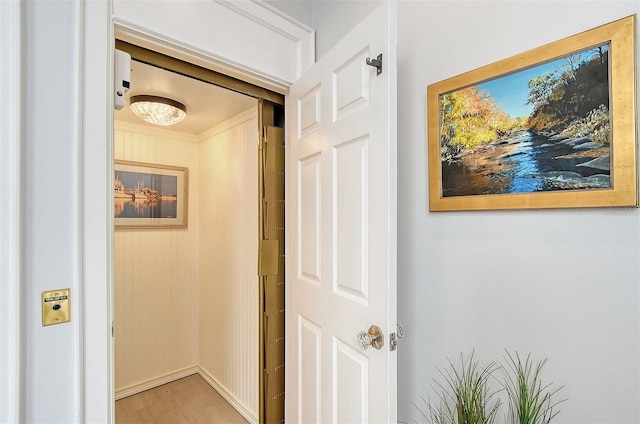 hall with light wood-type flooring and crown molding