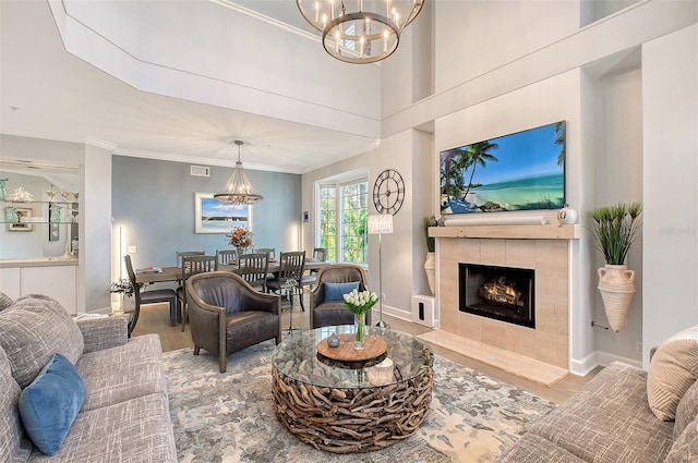 living room featuring a chandelier, light wood-type flooring, and a tiled fireplace