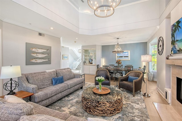 living room with crown molding, a high end fireplace, and an inviting chandelier