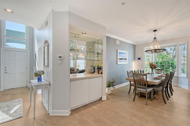 dining room featuring an inviting chandelier, light hardwood / wood-style flooring, and ornamental molding