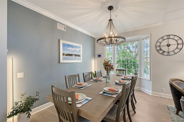 dining area featuring light wood-type flooring, an inviting chandelier, and ornamental molding