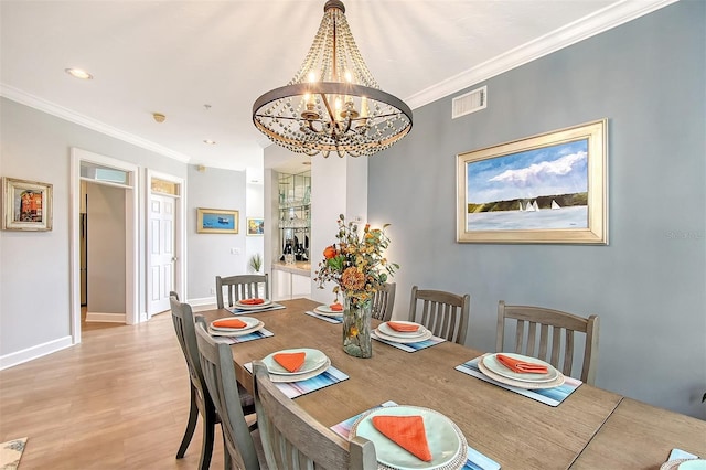 dining space featuring ornamental molding, light hardwood / wood-style flooring, and an inviting chandelier