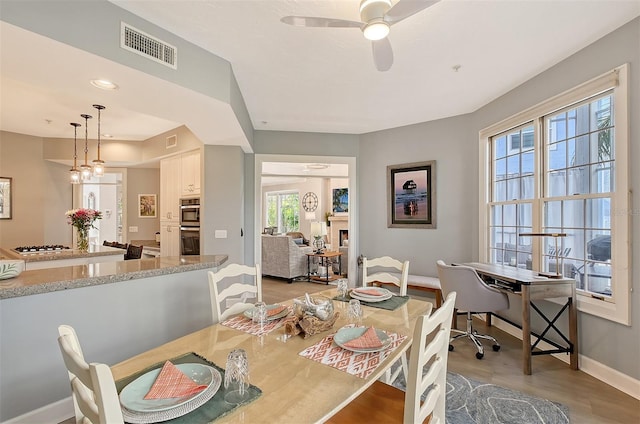 dining room featuring light wood-type flooring, ceiling fan, and a healthy amount of sunlight