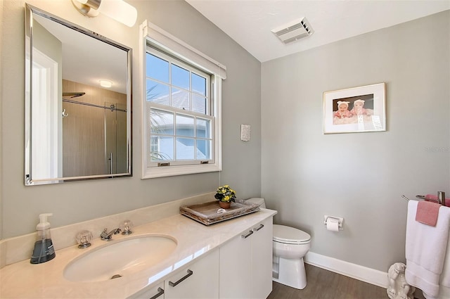 bathroom featuring a shower, wood-type flooring, vanity, and toilet