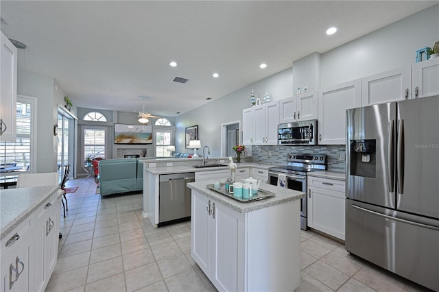 kitchen with sink, a center island, kitchen peninsula, stainless steel appliances, and white cabinets