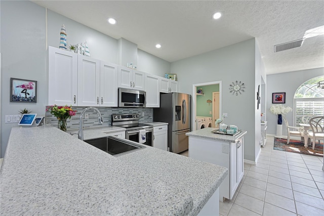 kitchen featuring a kitchen island, sink, kitchen peninsula, stainless steel appliances, and washer and clothes dryer