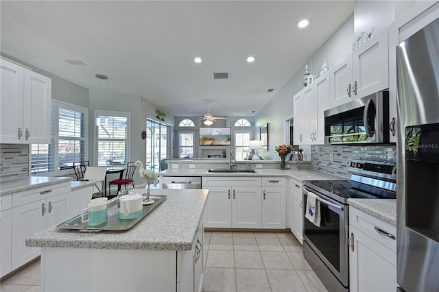 kitchen with sink, stainless steel appliances, white cabinets, a kitchen island, and kitchen peninsula