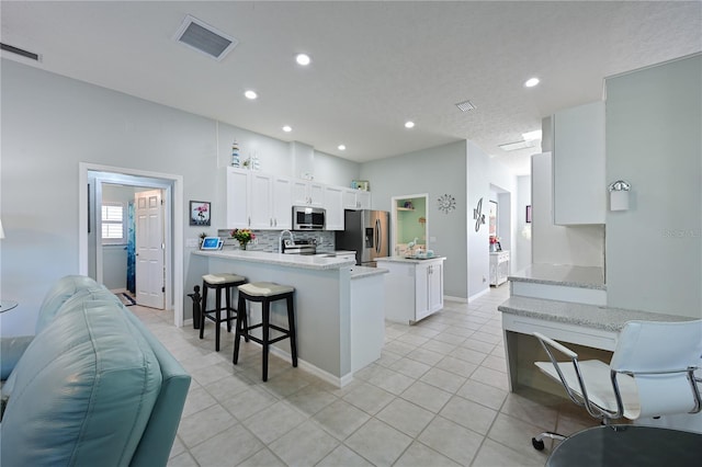 kitchen featuring stainless steel appliances, white cabinetry, a breakfast bar area, and kitchen peninsula