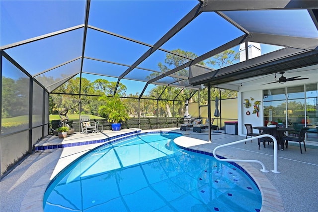 view of swimming pool with ceiling fan, glass enclosure, and a patio area