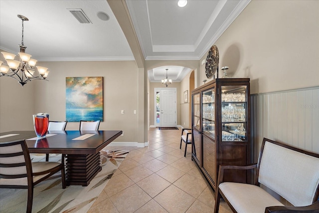 tiled dining space with a chandelier, a raised ceiling, and crown molding