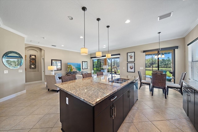 kitchen featuring a center island with sink, light tile patterned floors, sink, and hanging light fixtures