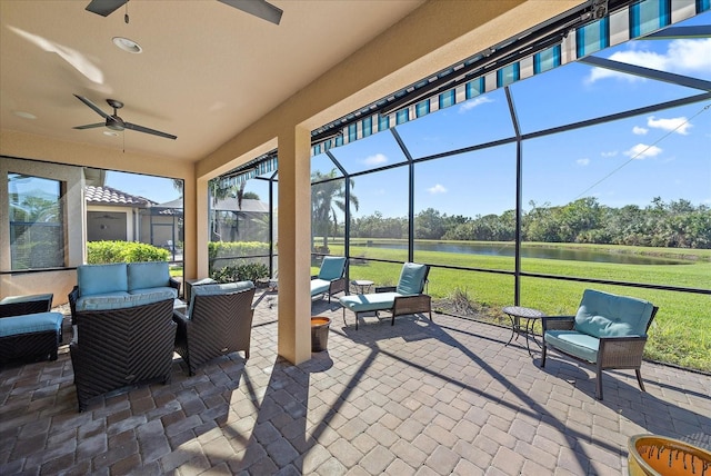 view of patio / terrace with a lanai, ceiling fan, a water view, and an outdoor hangout area