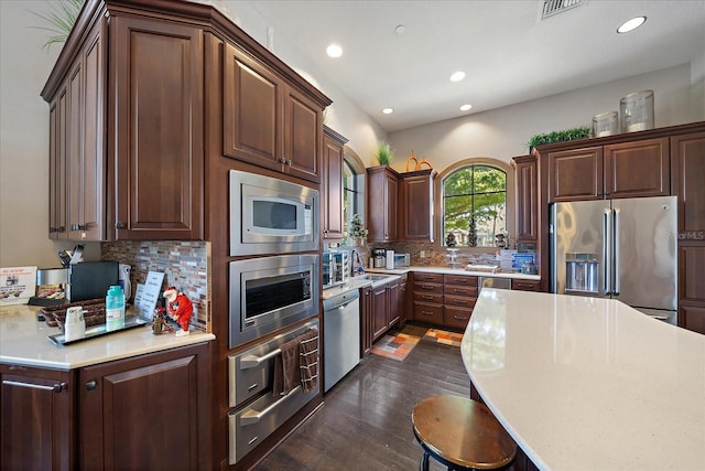 kitchen featuring dark brown cabinets, backsplash, stainless steel appliances, and dark hardwood / wood-style floors