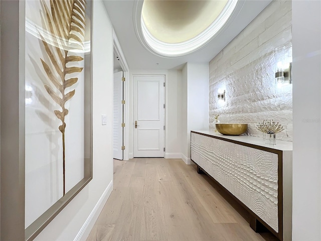 corridor with light hardwood / wood-style floors and a raised ceiling