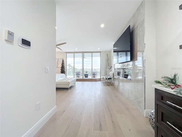 corridor featuring a wall of windows, light hardwood / wood-style flooring, and plenty of natural light