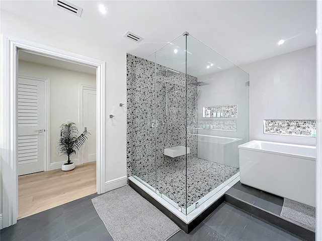 bathroom with wood-type flooring and shower with separate bathtub