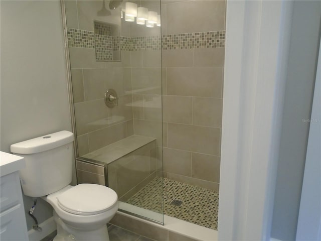 bathroom with tile patterned floors, vanity, toilet, and a tile shower