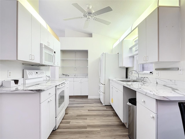 kitchen featuring sink, light hardwood / wood-style floors, vaulted ceiling, white appliances, and white cabinets