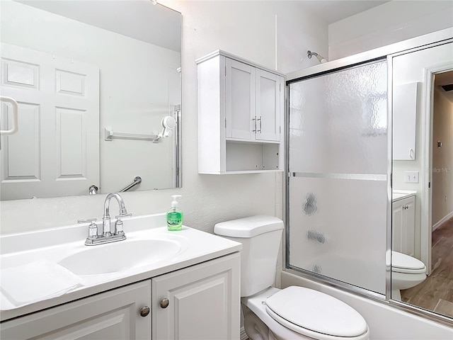 full bathroom with hardwood / wood-style floors, vanity, toilet, and combined bath / shower with glass door