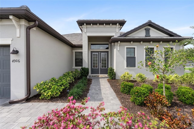 view of exterior entry with an attached garage and stucco siding