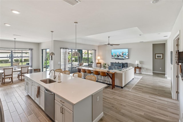 kitchen with open floor plan, decorative light fixtures, a kitchen island with sink, light countertops, and white cabinetry