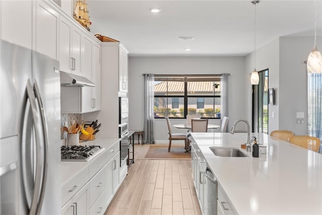 kitchen featuring appliances with stainless steel finishes, pendant lighting, light countertops, and a sink