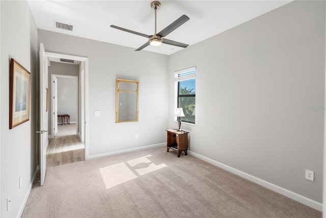 unfurnished bedroom featuring light carpet, ceiling fan, visible vents, and baseboards