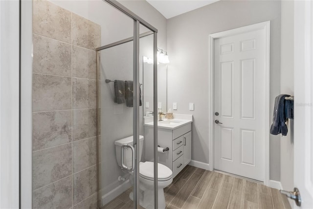 full bathroom with wood finish floors, toilet, a stall shower, vanity, and baseboards