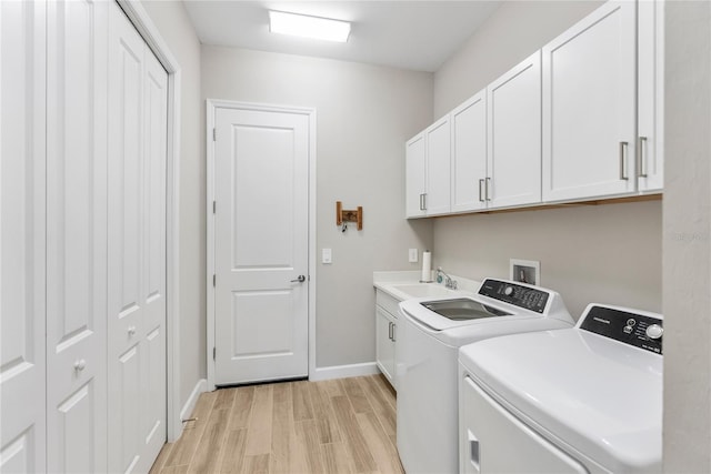 clothes washing area featuring cabinet space, baseboards, washing machine and clothes dryer, light wood-type flooring, and a sink