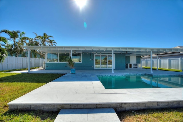 back of property with ceiling fan, a patio area, a fenced in pool, and a yard