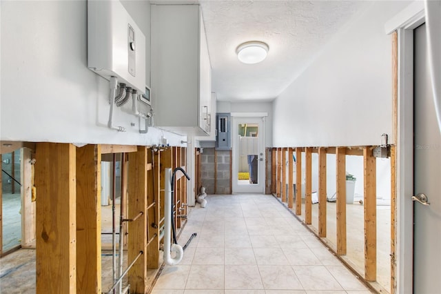 hallway featuring light tile patterned floors, a textured ceiling, plenty of natural light, and water heater