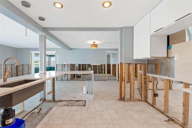 kitchen with white cabinetry, sink, light tile patterned floors, and decorative light fixtures