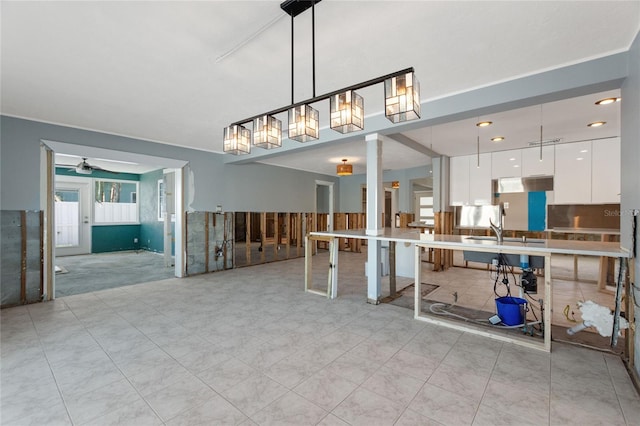 kitchen with white cabinetry, sink, ceiling fan, and hanging light fixtures