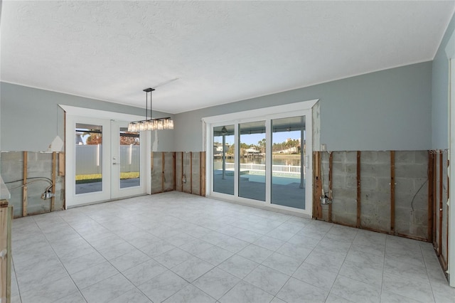 unfurnished dining area with light tile patterned flooring, tile walls, a textured ceiling, and a chandelier