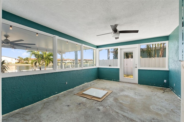 unfurnished sunroom with ceiling fan and a water view