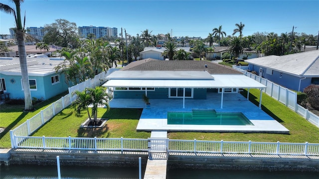 rear view of property featuring a patio area, a fenced in pool, and a yard